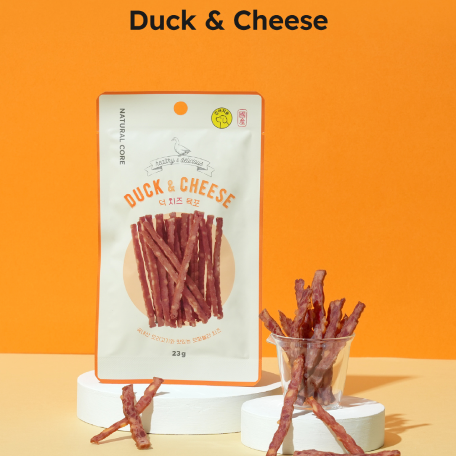 Duck & Cheese snack sticks with packaging on an orange background